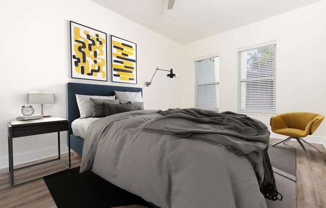 A bedroom with a bed, a chair, and a painting on the wall.