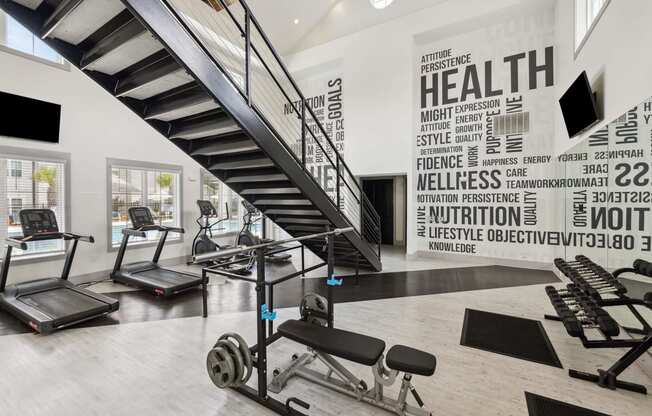 a gym with stairs and weights and a wall with words on it