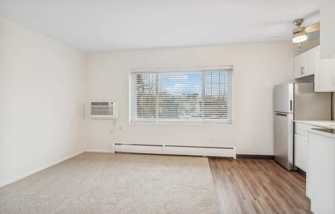 A kitchen with white cabinets and a window with blinds.