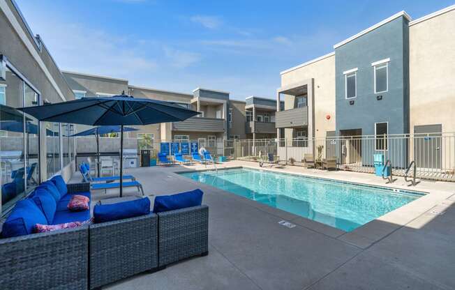 a pool with lounge chairs and umbrellas at the whispering winds apartments in pearland, at Loma Villas Apartments, San Bernardino, 92408