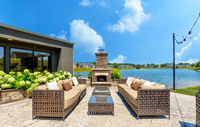 Outdoor entertainment area at Somerset Lakes Apartments, featuring a patio with a fireplace, seating, and views of the water