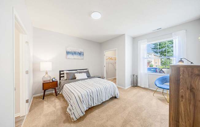 A bedroom with a bed, nightstand, and chair.