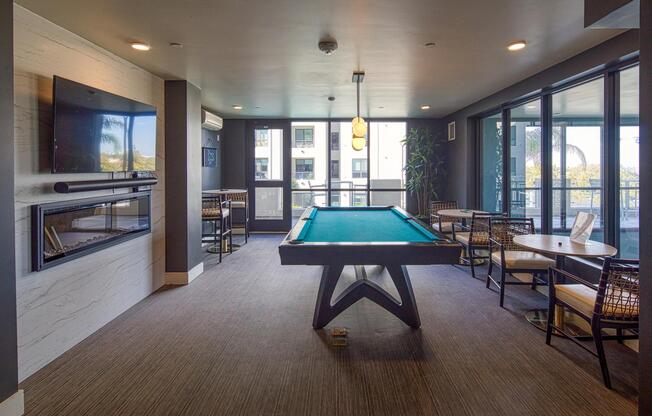 Stylish game lounge with a pool table, fireplace accent wall, and seating arranged for easy indoor entertainment.