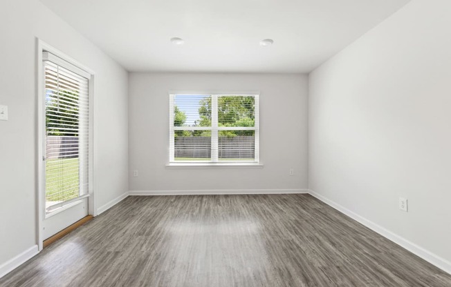 an empty living room with wood floors and a window