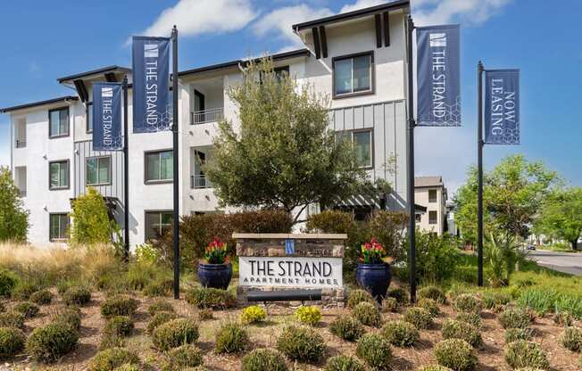 The Strand Apartment House is a white building with a sign in front of it.