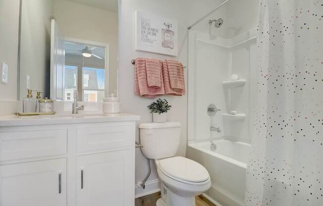 A white bathroom with a toilet, sink, and shower.