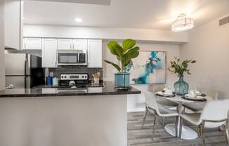 Newly renovated large dining area and kitchen with white cabinets, stainless steel appliances, and breakfast bar