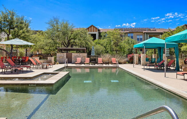 a swimming pool with chairs and umbrellas and a building in the background at Lakeline East Apartments, Texas, 78613