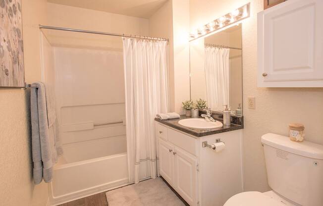 A white bathroom with a sink, toilet, and bathtub at Zinfandel Village Apartments, California, 95670
