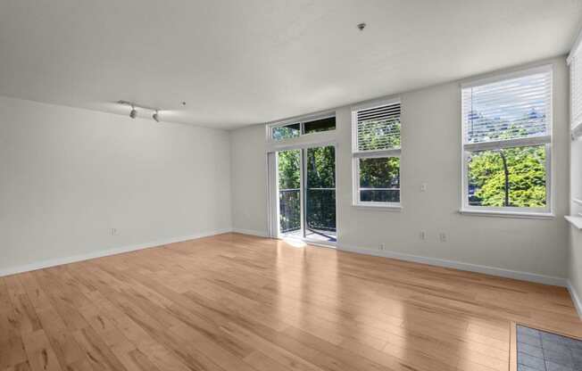 an empty living room with wood floors and a door to a balcony