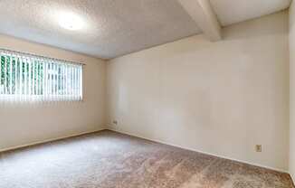 the spacious living room of an empty home with a window