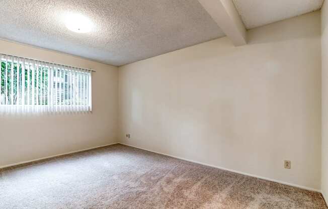 the spacious living room of an empty home with a window