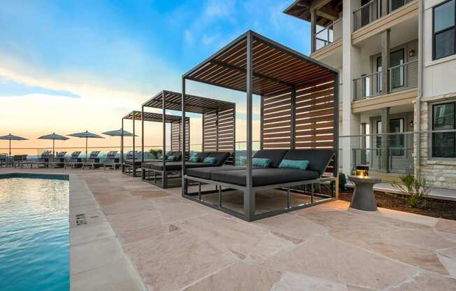 a pool with lounge chairs and umbrellas next to a building with a pool