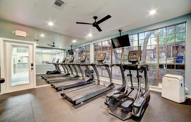 a gym with cardio machines and a tv