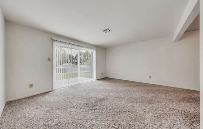 A room with a carpeted floor and a sliding glass door.