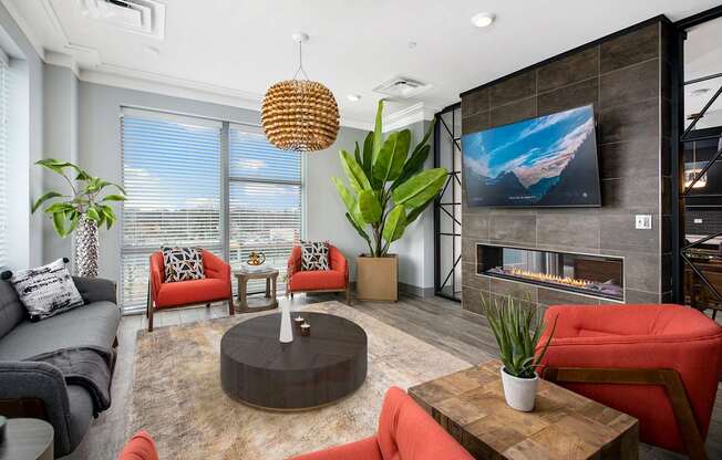 A modern living room with a grey couch, red chairs, and a fireplace.