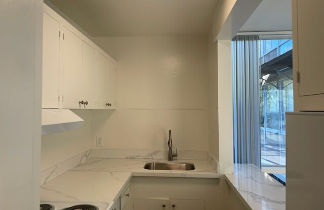 a white kitchen with a sink and a window