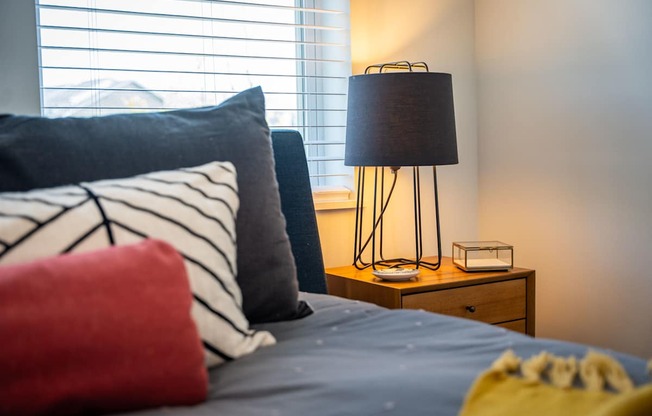 A bed with a red pillow and a lamp on a side table at the Mastlight.