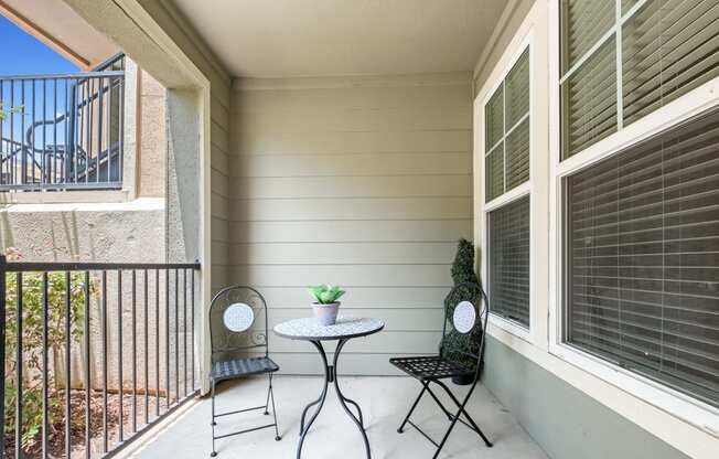 a patio with two chairs and a table on a balcony