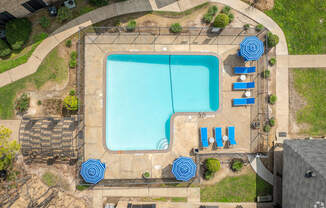 arial view of a swimming pool with blue umbrellas and chairs around it