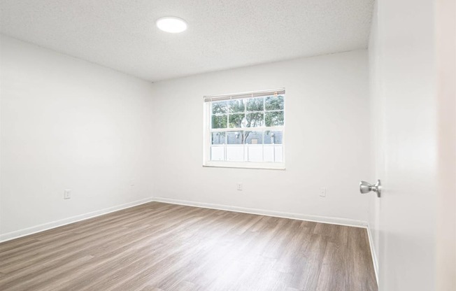 an empty room with white walls and a window