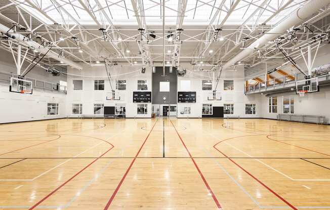 A large indoor basketball court with wooden floors and a high ceiling with lights.