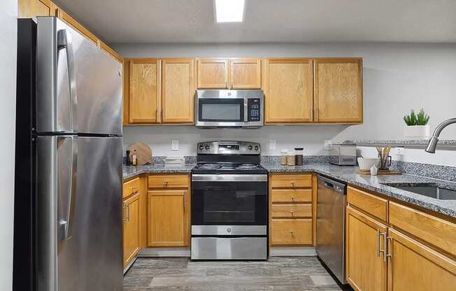 Model Kitchen with Wood-Style Flooring and Oak Cabinets at Retreat at Stonecrest Apartments located in Lithonia, GA.