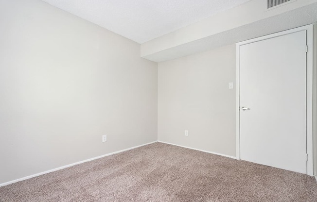A room with a carpeted floor and a white door.