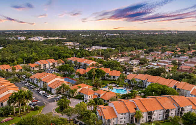 A sunset view of a residential area with houses and a pool.