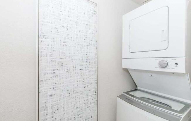 A white dryer is next to a white wall with a list of items on it.