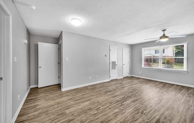 an empty living room with a window and a ceiling fan