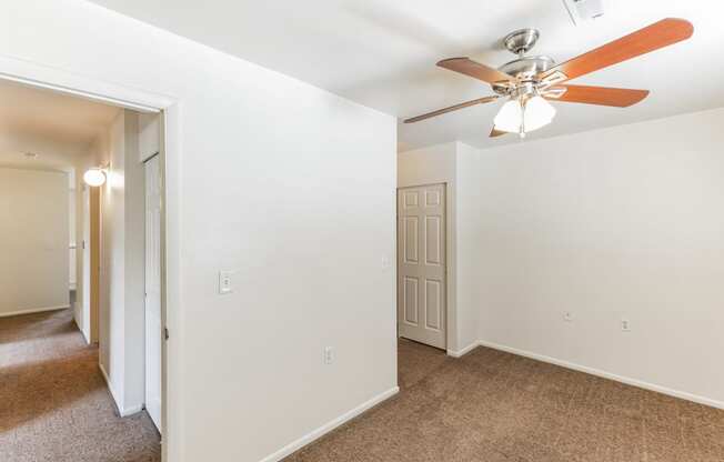 a renovated living room with a ceiling fan and white walls