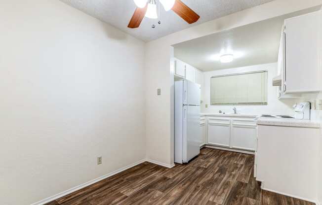 an empty kitchen with white appliances and a white refrigerator