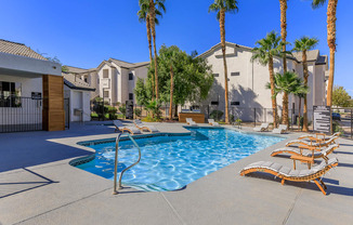 A pool surrounded by palm trees and lounge chairs.