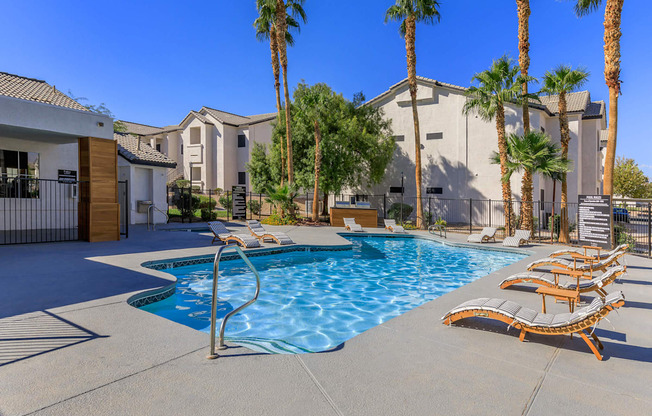 A pool surrounded by palm trees and lounge chairs.