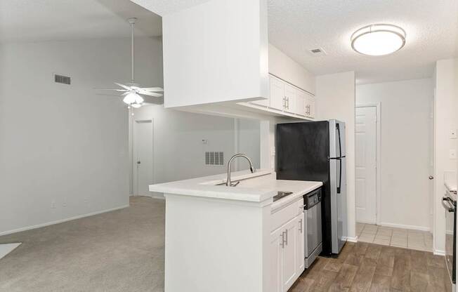 A kitchen with white cabinets and a black refrigerator.