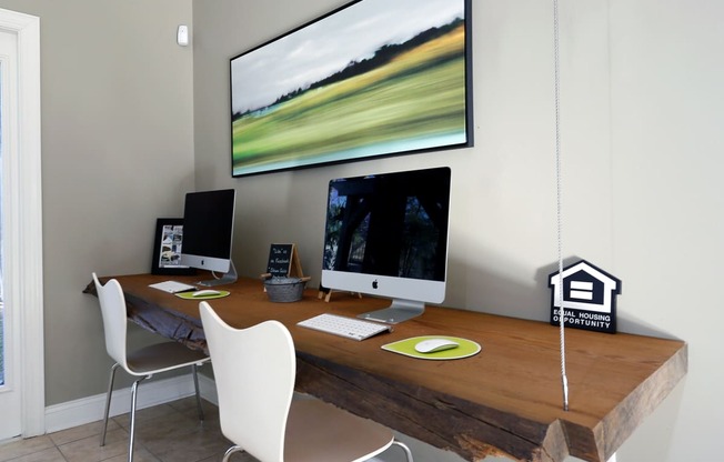 a home office with a desk with two computers and a large monitor on the wall