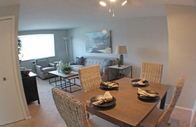 a dining room with a table and chairs and living room in the background