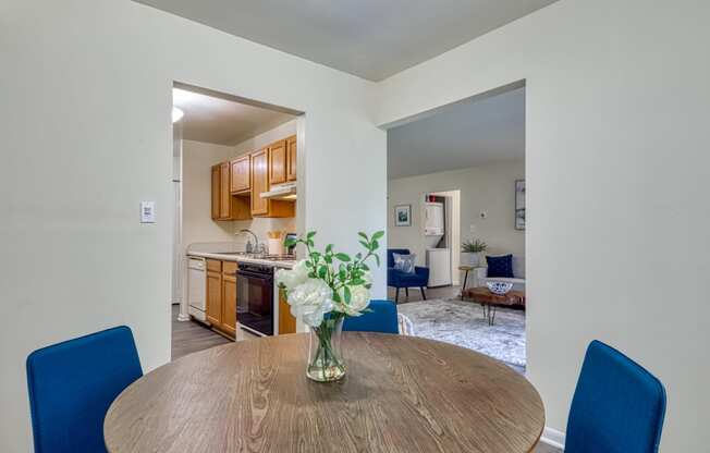 a dining room table with two blue chairs and a vase of flowers