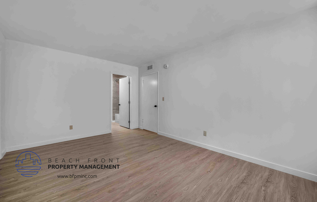 a bedroom with hardwood floors and white walls