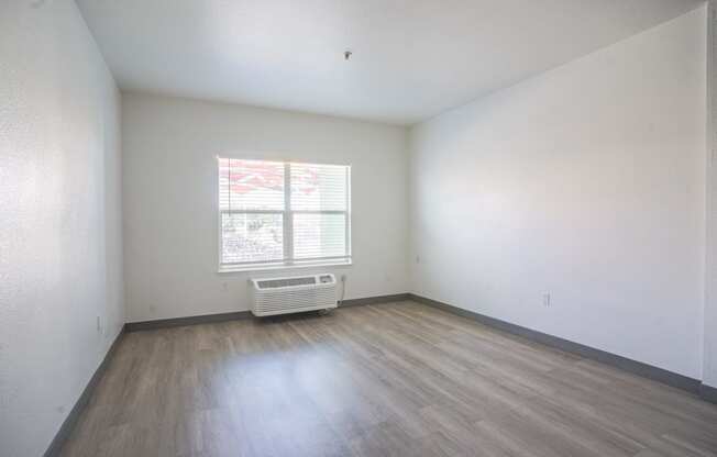 the living room of an empty house with wooden floors and a window