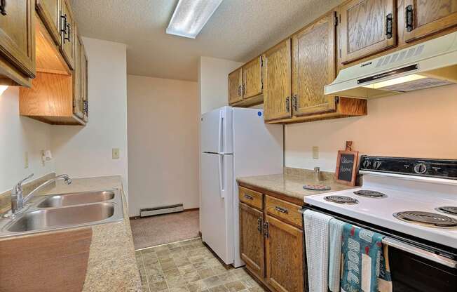 a kitchen with white appliances and wooden cabinets. Fargo, ND Pacific South Apartments.