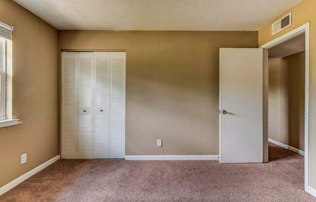 an empty room with a closet and an open door