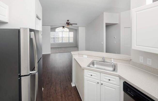 A kitchen with a black refrigerator and white cabinets.