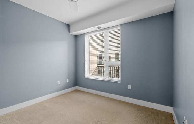 an empty bedroom with a large window and blue walls