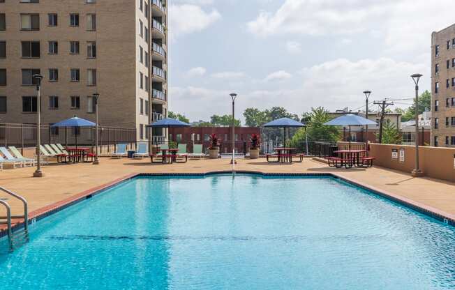 a swimming pool with tables and umbrellas in front of a building