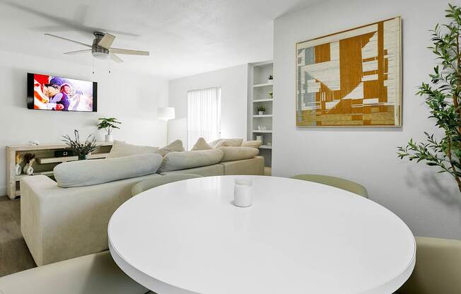 A living room with a white table and a television on the wall.