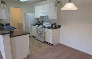A kitchen with white cabinets and a black countertop.