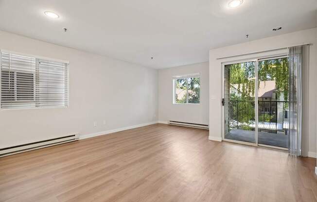 A room with wooden floors and a sliding glass door leading outside.