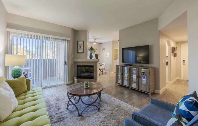 A living room with a green couch, a coffee table, and a television.